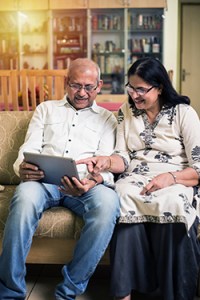 A couple sits on the couch with their tablet 