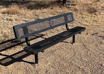 A metal memorial bench is shown alongside a crusher fine trail