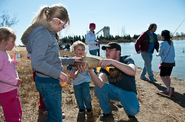 Man holding and showing fish to children