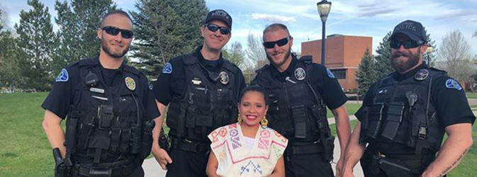 Male police officers take a photo with a traditional Cinco de Mayo dancer