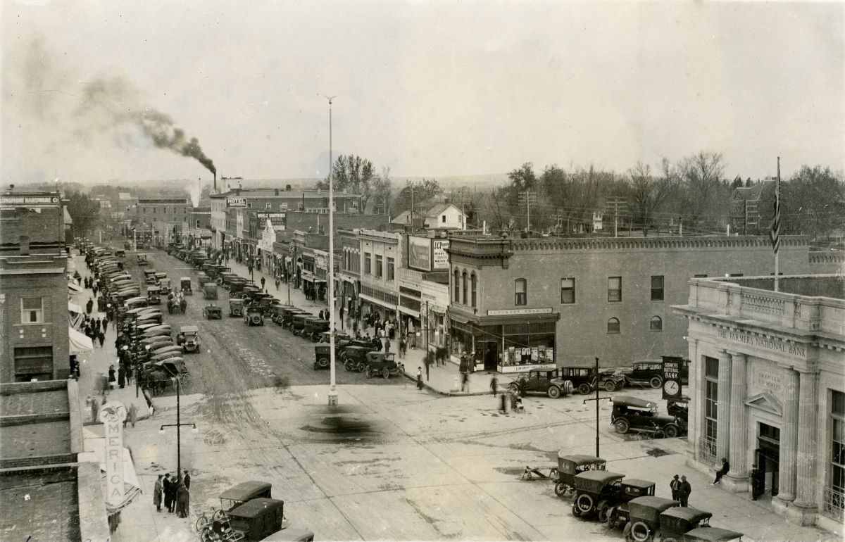 Black and white image of main street with tall flag pole at center