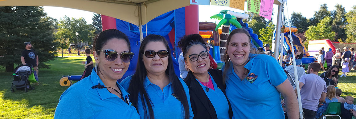 Four smiling staff standing together with festival goers in the background.