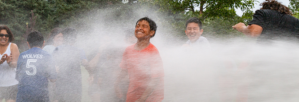 Youth enjoy spray from a fire hose on a hot day at the youth center