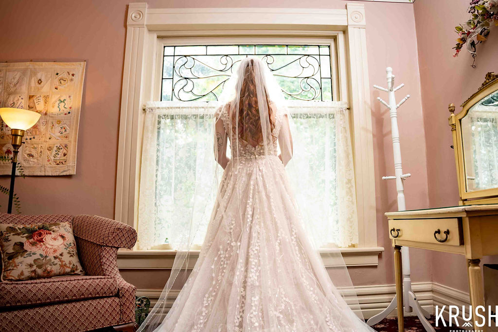 Bride looking out a stained glass window in a pink room