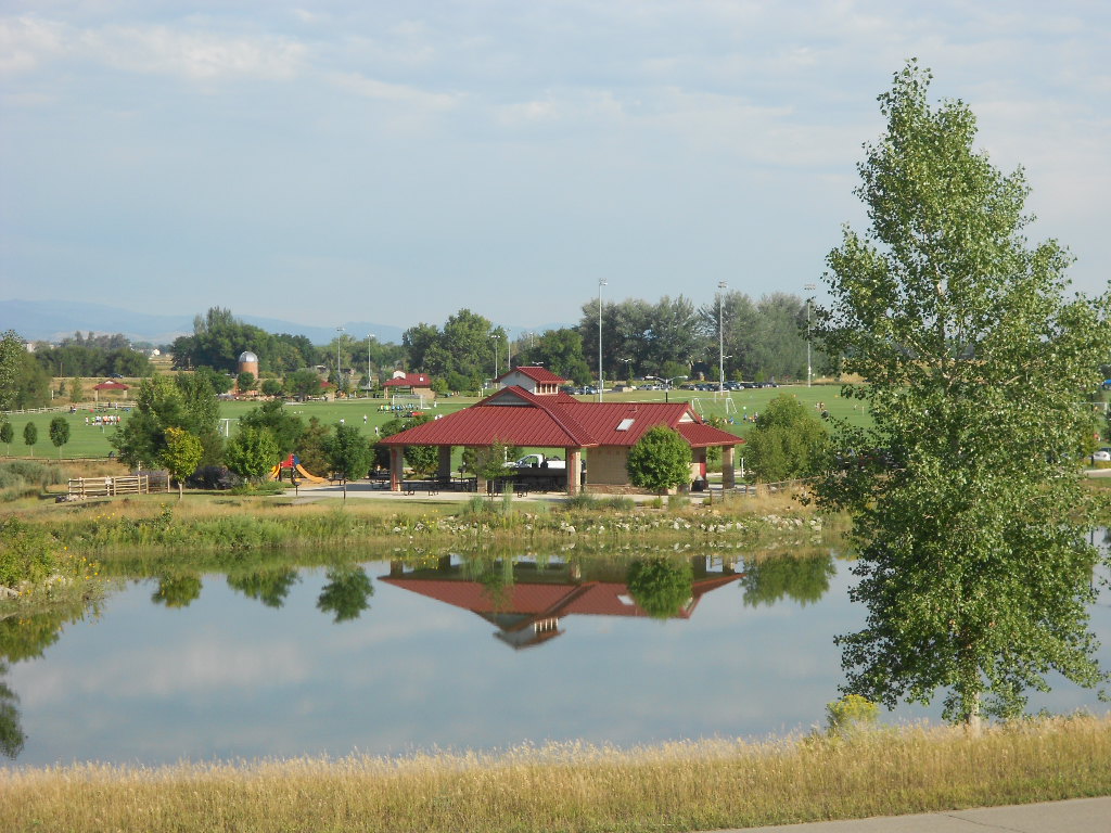 The E2 park shelter at Sandstone Ranch viewed across the pond, with a reflection in the water.