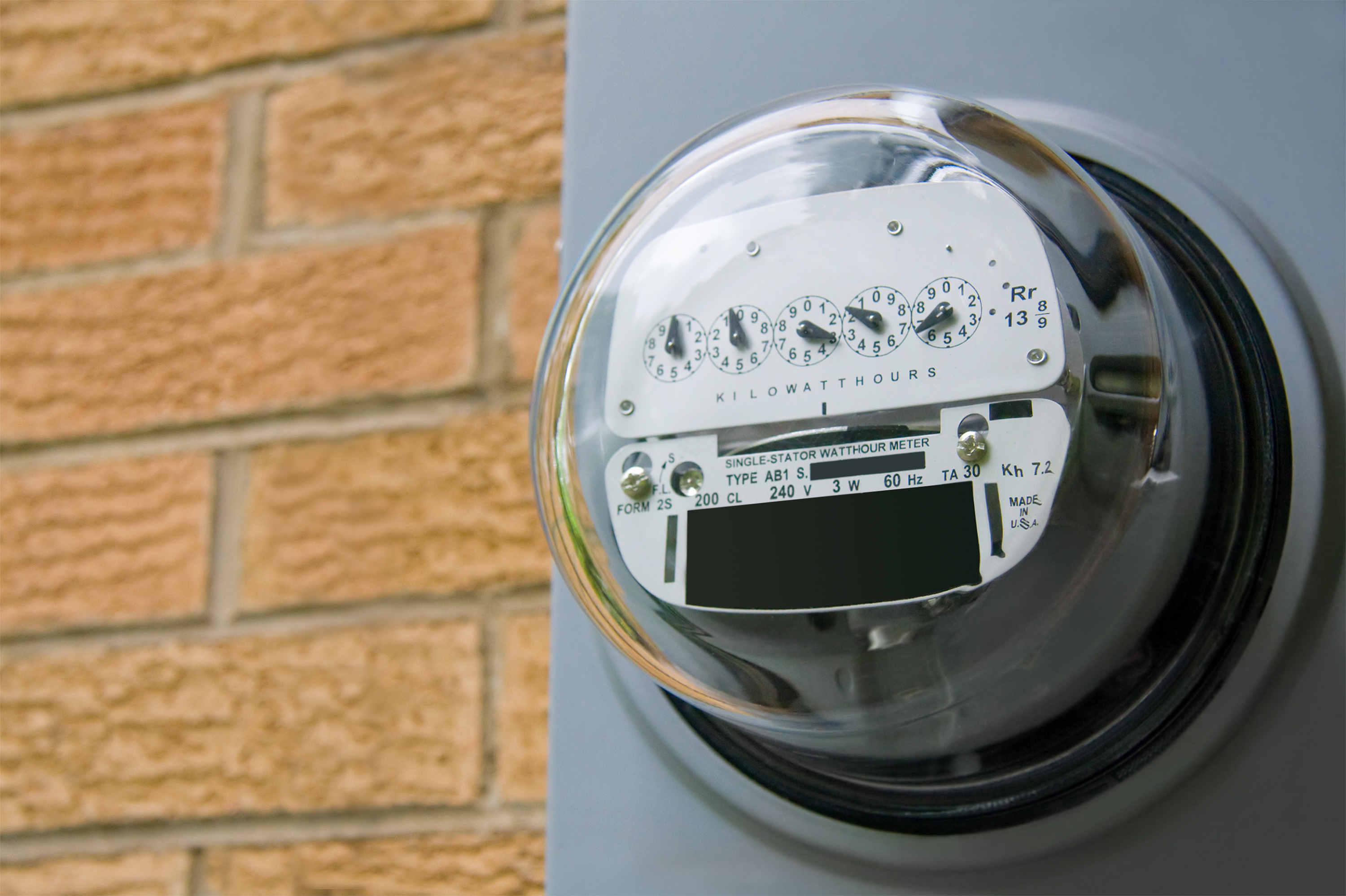 Mechanical electric meter on the side of a brick wall