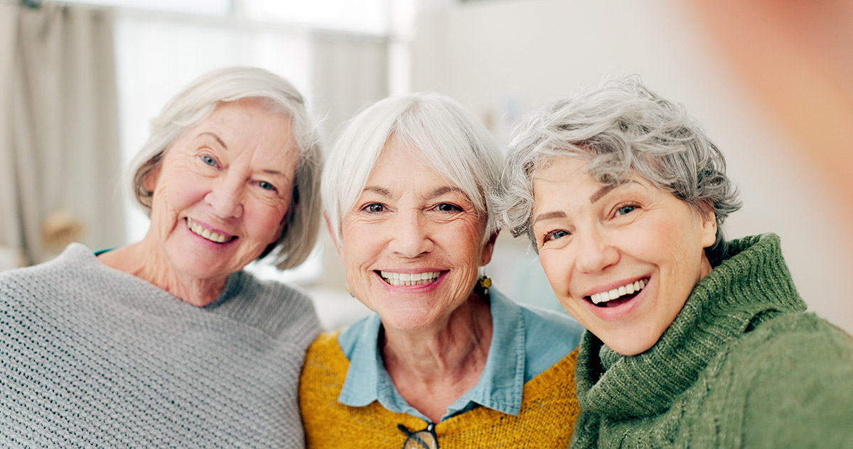 Three senior women smile for the camera.