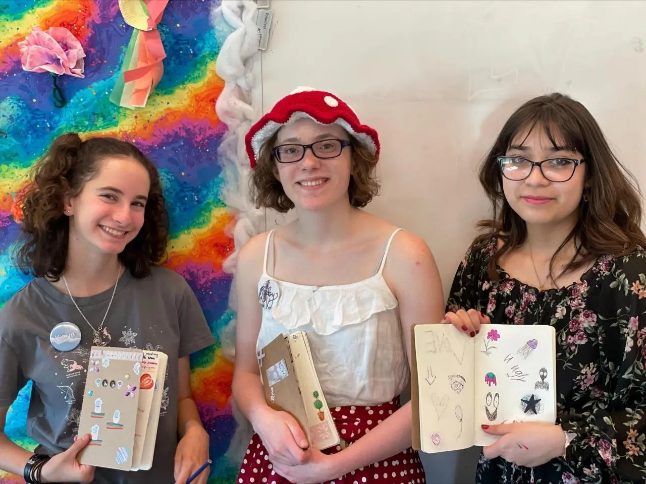 Three teenage girls holding their artwork