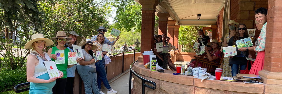 Group of adults showing off their watercolor painting on the porch of the Callahan House.