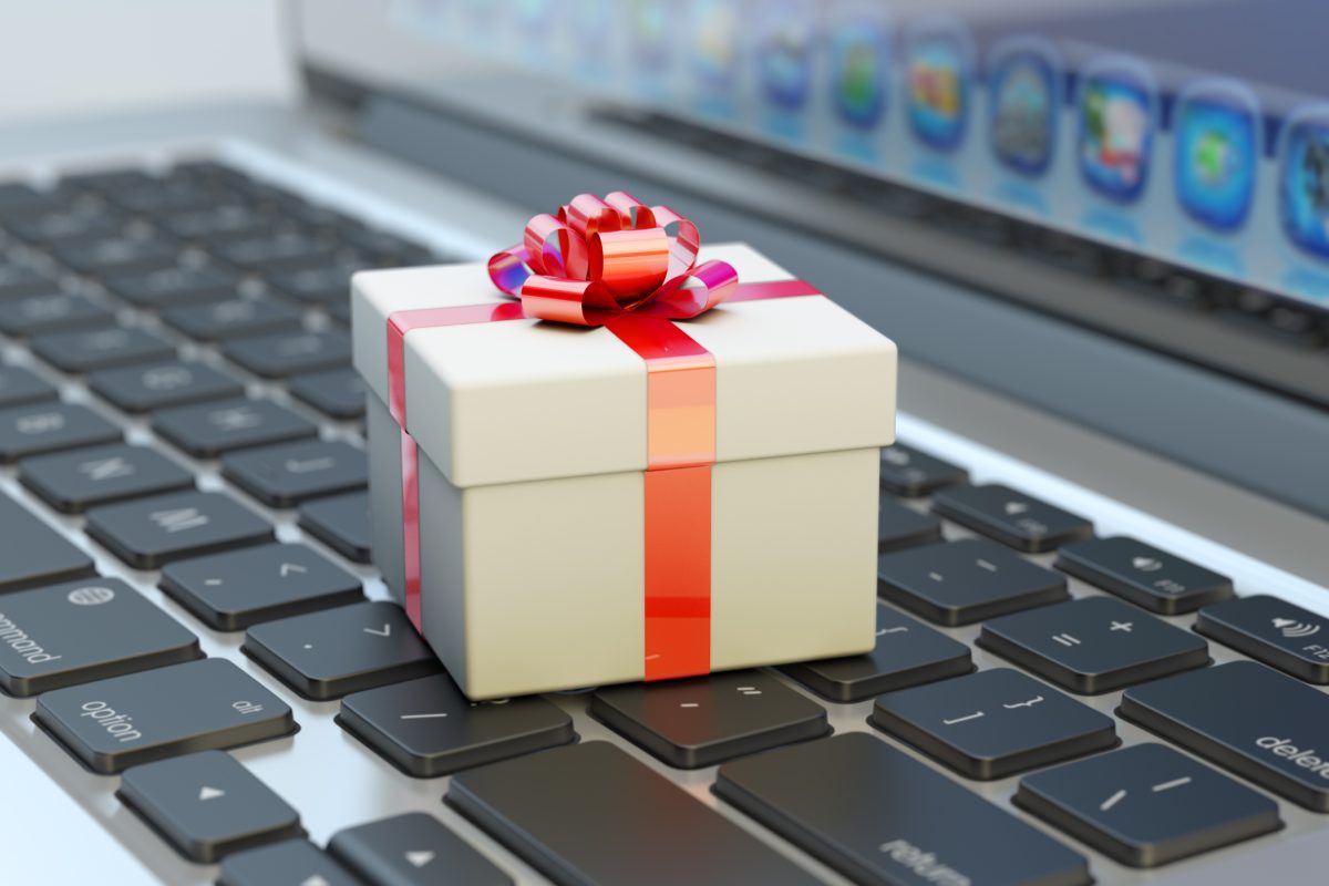 Close up of a gift wrapped with a red ribbon sitting on a laptop keyboard