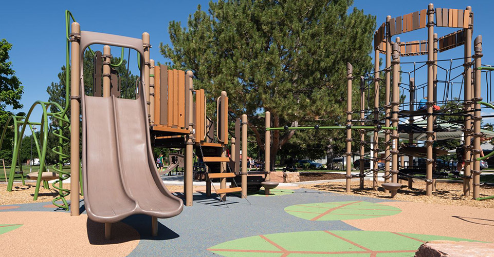 A playground is surrounded by evergreens at Loomiller Park